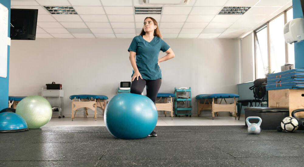 Adult woman standing in rehabilitation room with training equipment